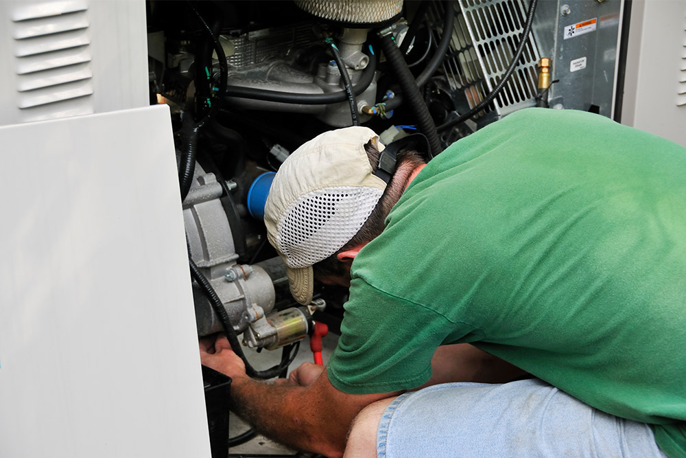Generator technician working on a standby generator. Learn more about us at Benchmark Electric. LLC